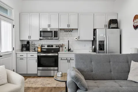 a kitchen with stainless steel appliances granite countertop a stove a sink a microwave a refrigerator and cabinets