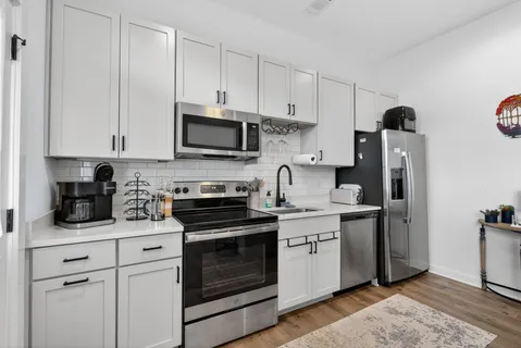 a kitchen with stainless steel appliances granite countertop white cabinets sink and refrigerator