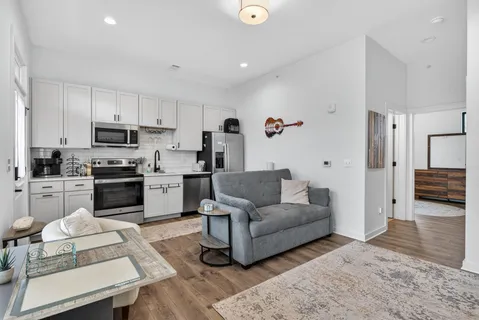 a living room with furniture a kitchen island a stove and a refrigerator