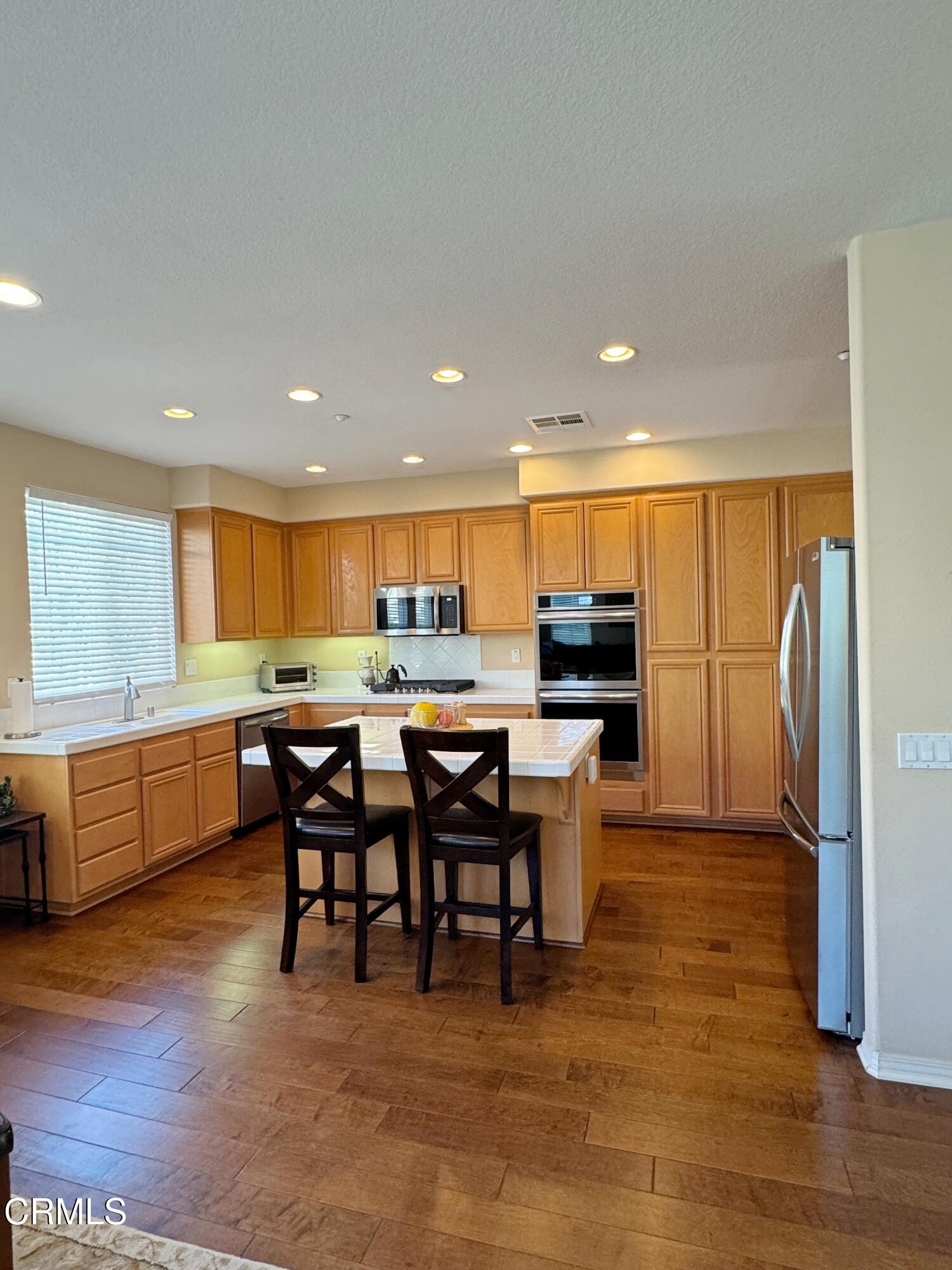 1240 Bayside Lane Oxnard, CA 93035 - Photo 27 of 69 a kitchen with a dining table chairs and refrigerator