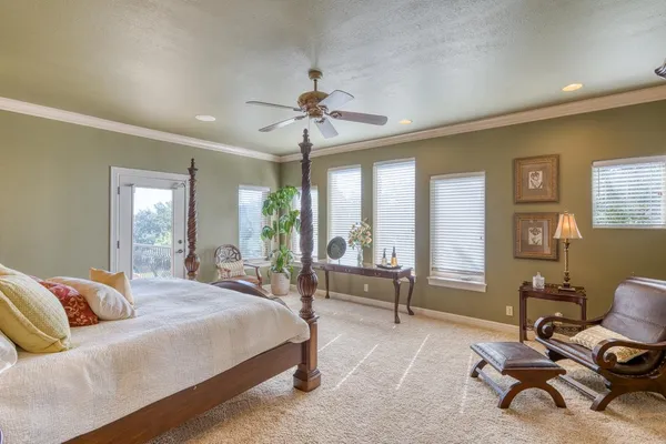 a bedroom with a bed couch and large windows