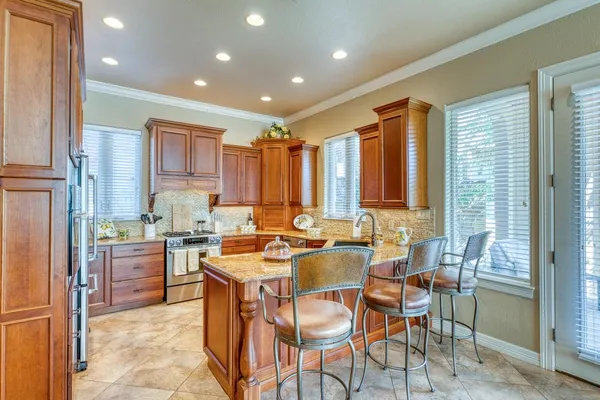a view of a kitchen with kitchen island granite countertop lots of white stainless steel appliances a dining table and chairs