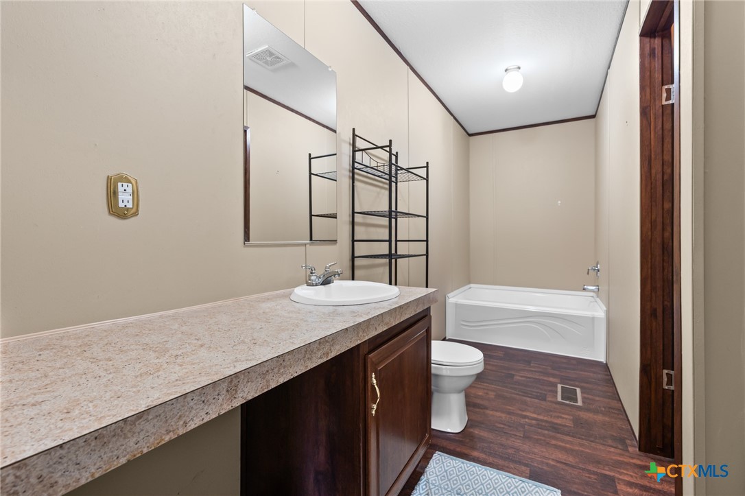 996 County Road 421 Evant, TX 76525 - Photo 12 of 48 a bathroom with a granite countertop sink a toilet a mirror and shower