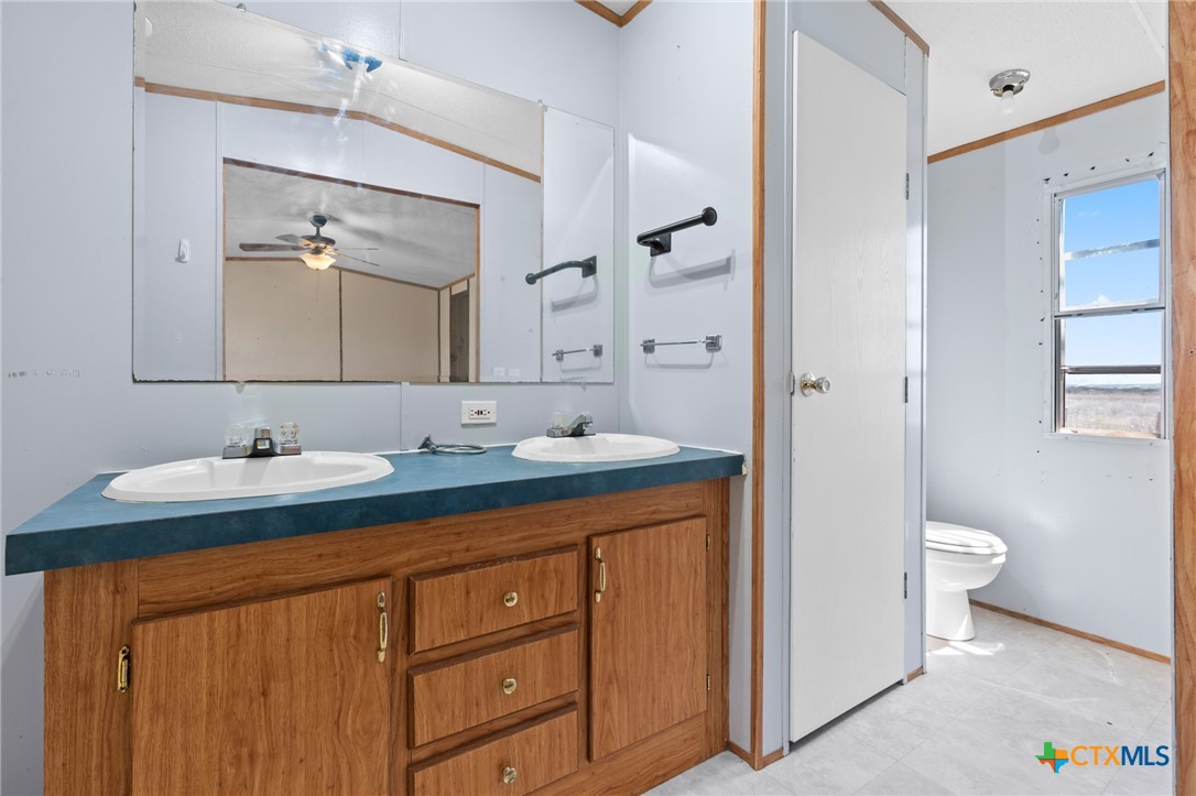 996 County Road 421 Evant, TX 76525 - Photo 28 of 48 a bathroom with a granite countertop sink mirror and toilet