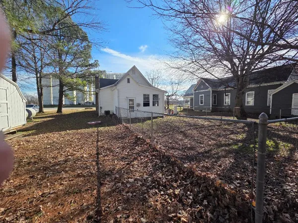 a backyard of a house with large trees and brick walls