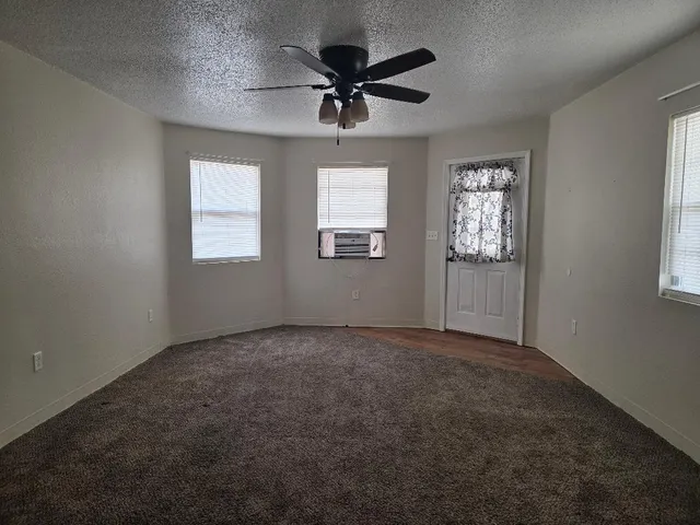 an empty room with windows and fan