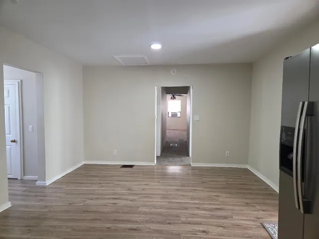 a view of an empty room with wooden floor and a mirror