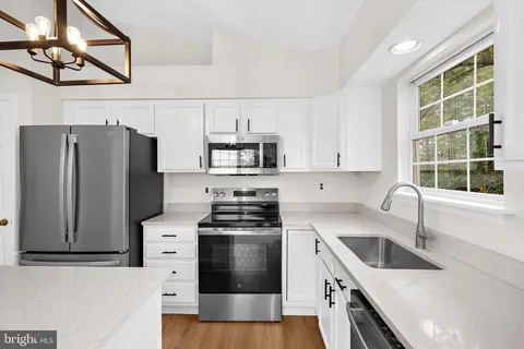a kitchen with granite countertop a sink a counter space appliances and cabinets