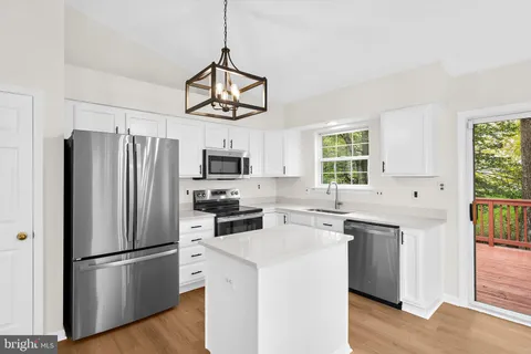 a kitchen with stainless steel appliances a refrigerator a stove a sink and white cabinets