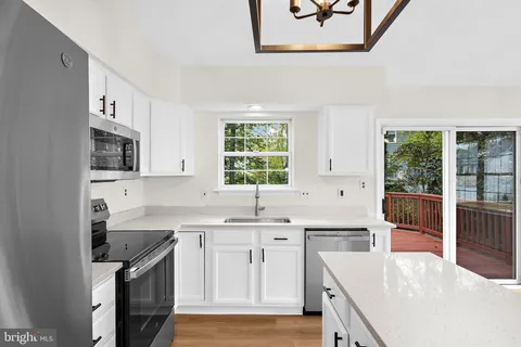 a kitchen with stainless steel appliances granite countertop a sink a stove a refrigerator cabinets and a window