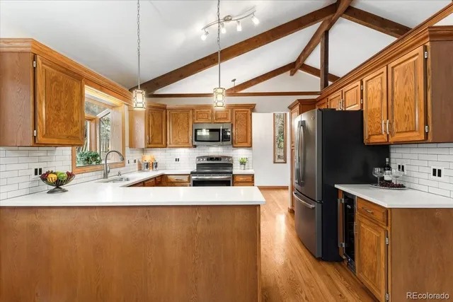 a kitchen with stainless steel appliances granite countertop a refrigerator a sink dishwasher a stove with wooden cabinets and floor