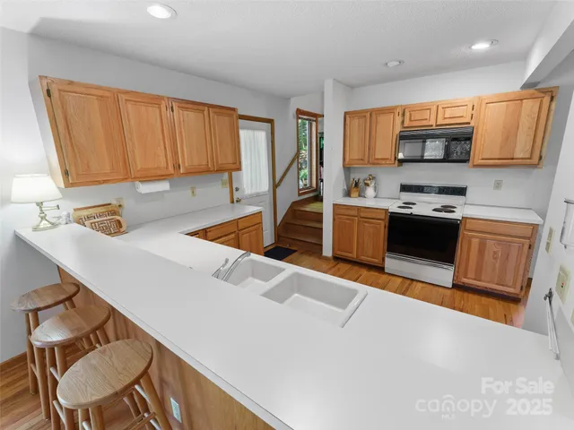 a kitchen with stainless steel appliances granite countertop a sink dishwasher stove top oven and cabinets with wooden floor