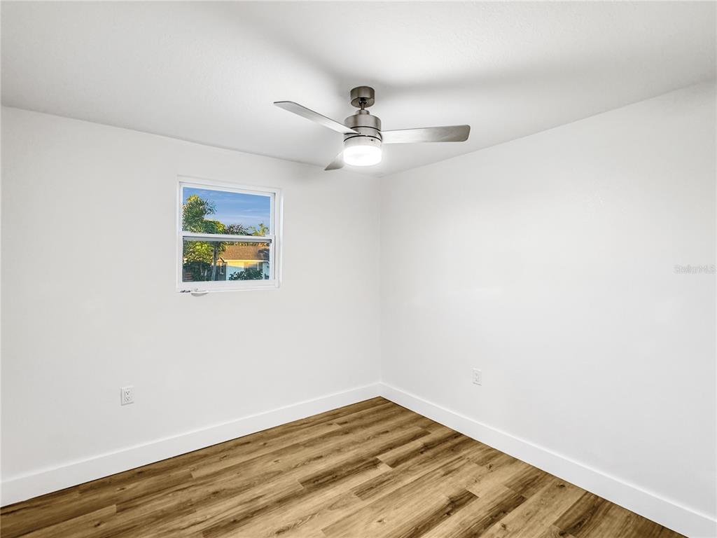 13739 Coco Avenue Hudson, FL 34667 - Photo 13 of 25 an empty room with wooden floor ceiling fan and windows