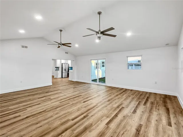 a view of empty room with wooden floor and ceiling fan