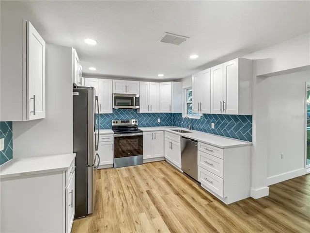 a kitchen with granite countertop a refrigerator stove top oven and sink