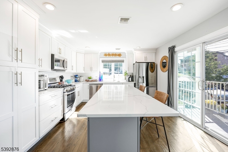 615 Prospect Avenue Fairview, NJ 07022 - Photo 6 of 18 a large white kitchen with granite countertop a stove a sink a refrigerator and white cabinets with wooden floor