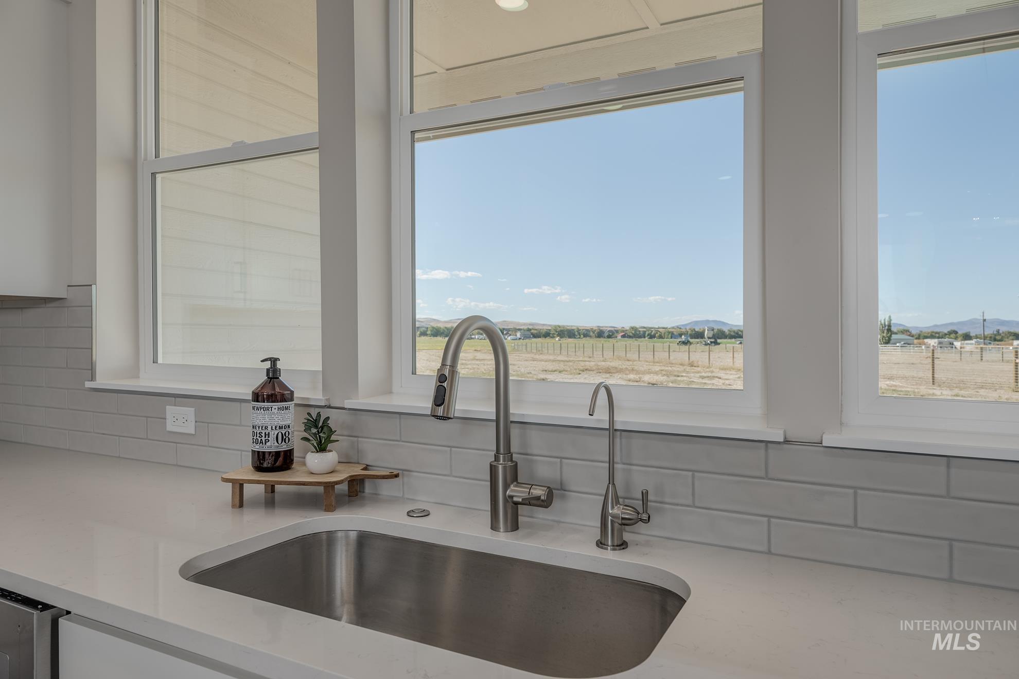 1371 Hansen Road Weiser, ID 83672 - Photo 15 of 44 Stainless steel undermount sink, gooseneck pull-down faucet, dedicated water dispenser, light-toned subway tile backsplash, and white countertop