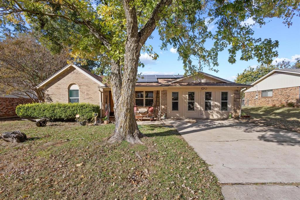 Ranch-style house with solar panels, a front yard, brick siding, and a patio