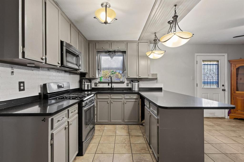 1417 Morrison Drive Denison, TX 75020 - Photo 11 of 30 Kitchen with a peninsula, appliances with stainless steel finishes, decorative light fixtures, and light tile patterned floors