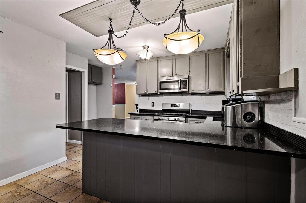 1417 Morrison Drive Denison, TX 75020 - Photo 12 of 30 Kitchen with tasteful backsplash, appliances with stainless steel finishes, a peninsula, dark stone countertops, and dark tile patterned flooring