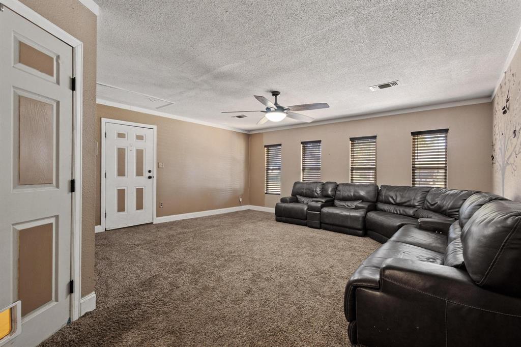 1417 Morrison Drive Denison, TX 75020 - Photo 14 of 30 Carpeted living area with a textured ceiling, healthy amount of natural light, ornamental molding, and a ceiling fan