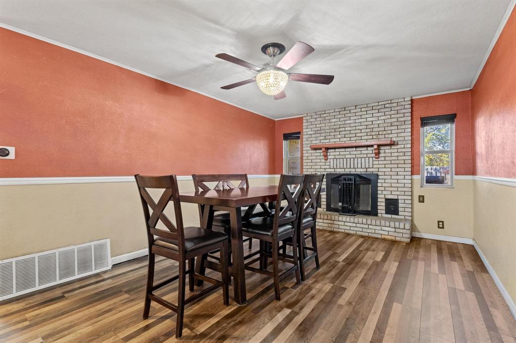 1417 Morrison Drive Denison, TX 75020 - Photo 8 of 30 Dining area featuring wood finished floors, ornamental molding, a fireplace, a ceiling fan, and a textured wall