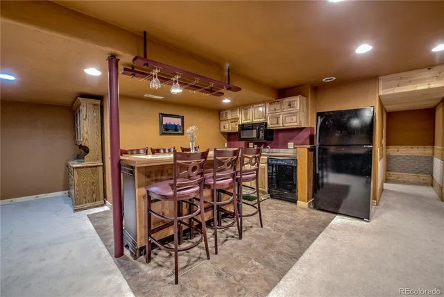 a kitchen with stainless steel appliances kitchen island granite countertop a refrigerator and chairs