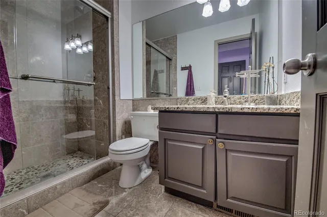 a bathroom with a granite countertop toilet sink and mirror