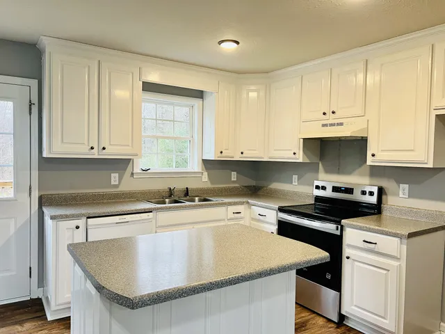 a kitchen with kitchen island granite countertop a sink a stove and cabinets