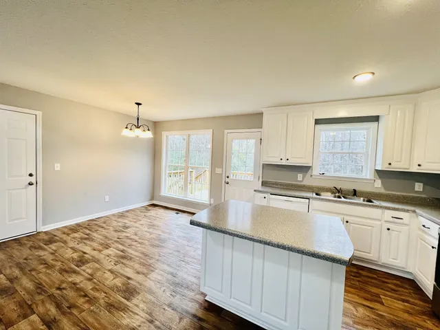 a kitchen with a stove a sink a refrigerator a window and white cabinets