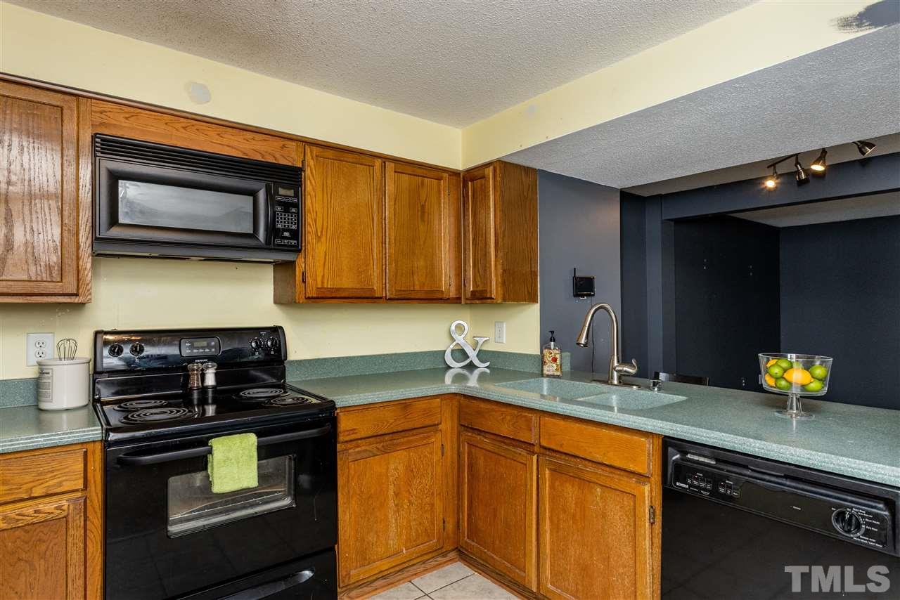 7720 Sandra Lane Raleigh, NC 27615 - Photo 4 of 25 a kitchen with stainless steel appliances granite countertop a sink stove and microwave