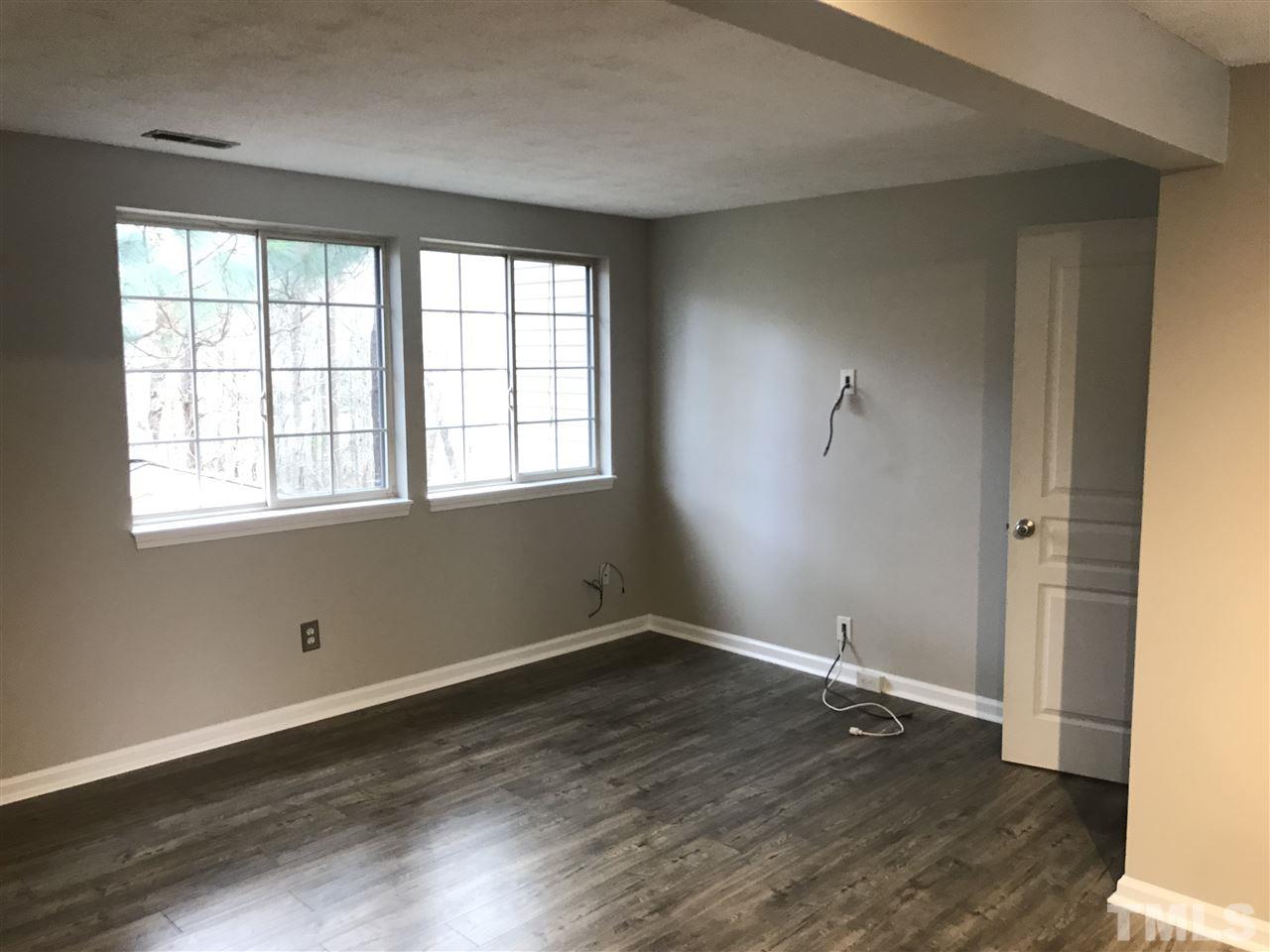 7720 Sandra Lane Raleigh, NC 27615 - Photo 7 of 25 an empty room with wooden floor and windows