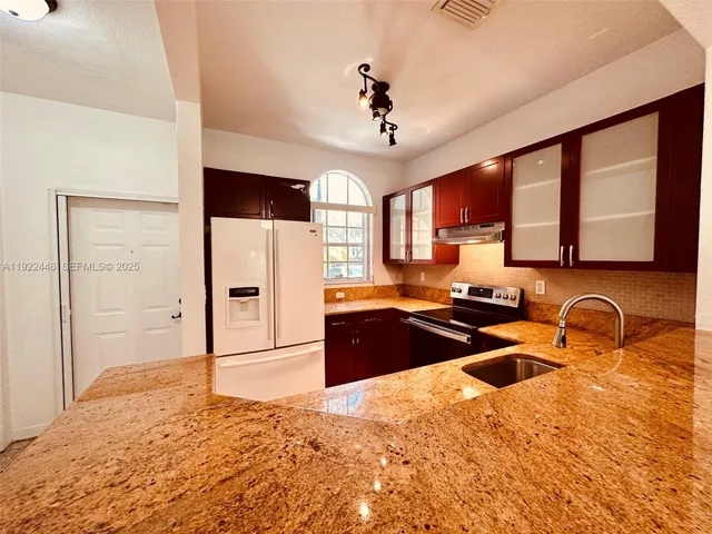 a kitchen with stainless steel appliances granite countertop a sink stove and refrigerator