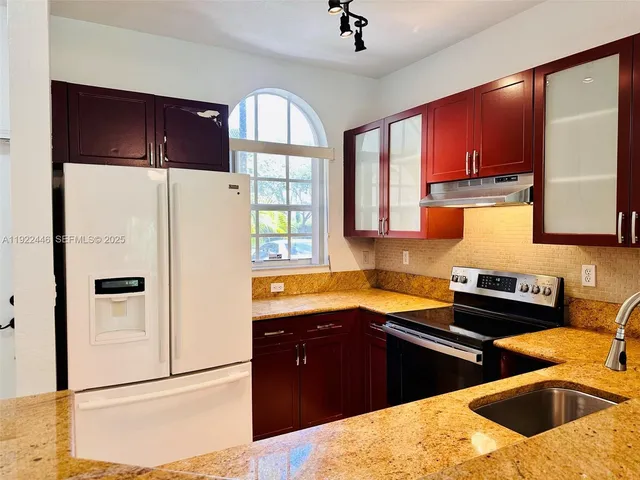 a kitchen with stainless steel appliances granite countertop a refrigerator a sink and a stove