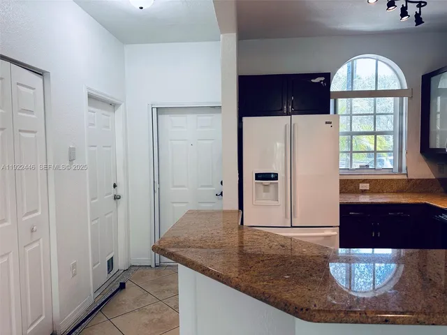 a view of kitchen with granite countertop a refrigerator and a stove top oven