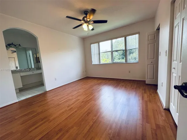 an empty room with wooden floor fan and windows