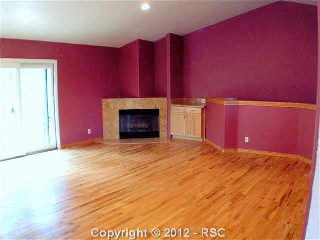 8211 Inca Road Larkspur, CO 80118 - Photo 5 of 24 Main level great room/living room showing patio doors to the deck, and the gas fireplace.