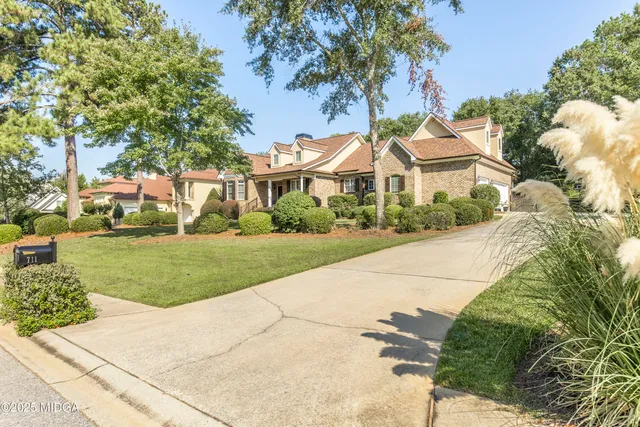 a front view of a house with a garden and tree