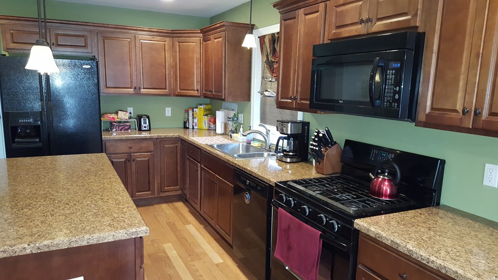 4 Mary Street Springfield, MA 01118 - Photo 7 of 16 a kitchen with granite countertop a stove top oven a sink dishwasher and a refrigerator with wooden cabinets