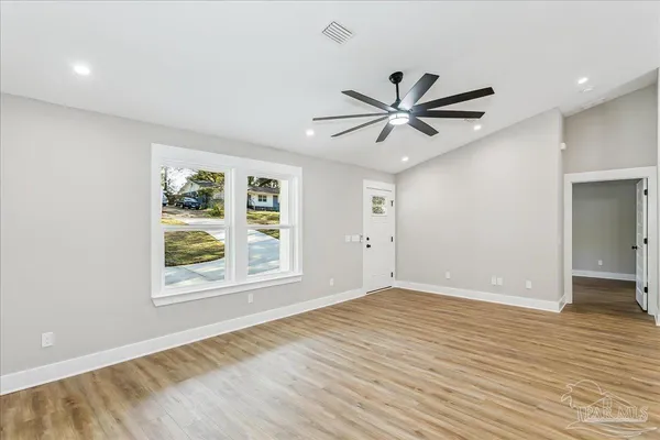 a view of an empty room with window and a ceiling fan