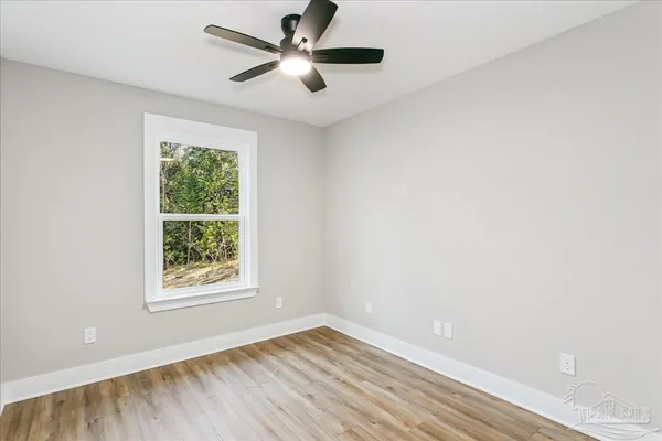 an empty room with a window and a fan