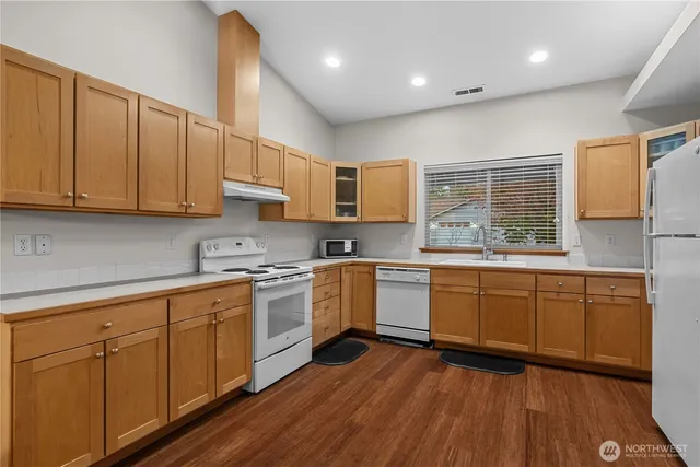 a kitchen with stainless steel appliances granite countertop wooden cabinets granite counter tops and a hard wood floors