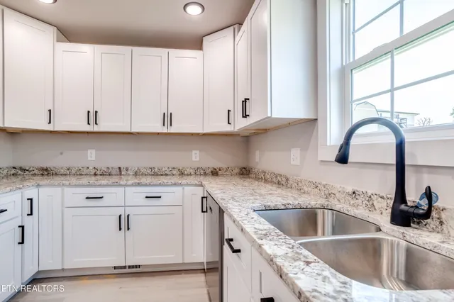 a kitchen with granite countertop a sink and white cabinets