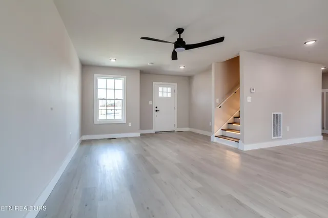 a view of an empty room with wooden floor and a window