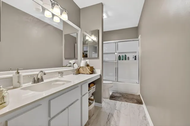 a spacious bathroom with a granite countertop sink a shower and a mirror