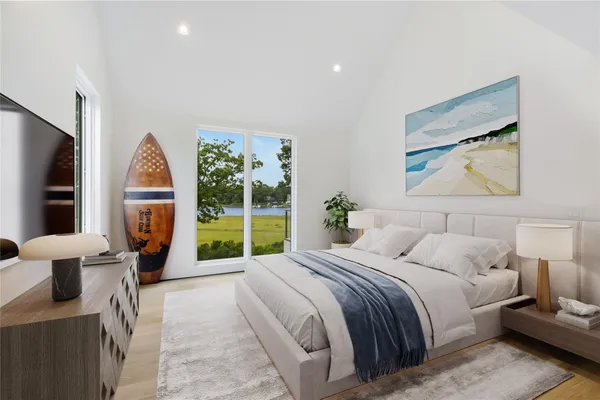 a bedroom with a bed a large window and potted plant on the dresser