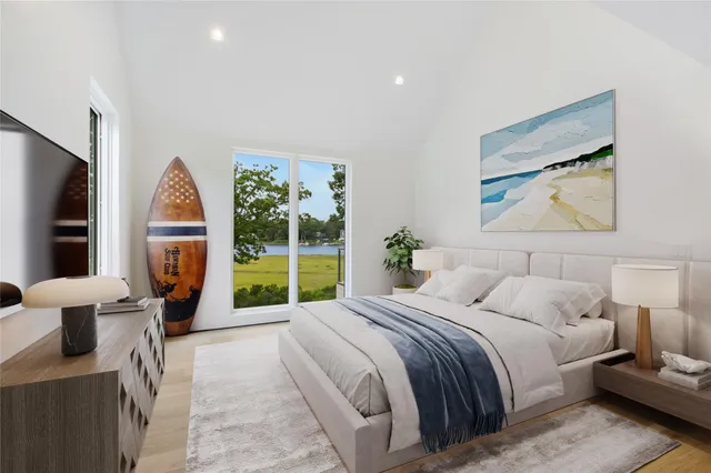 a bedroom with a bed a large window and potted plant on the dresser