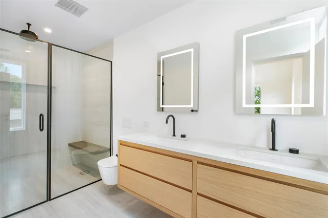 a bathroom with a double vanity sink toilet and shower