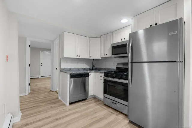 a kitchen with refrigerator a stove and white cabinets