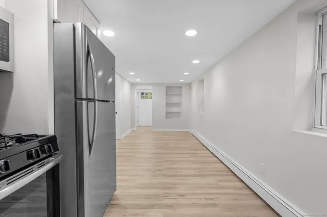 a view of an empty room with a window and wooden floor